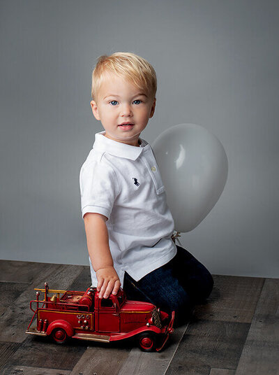 Little boy with a balloon and a firetruck.