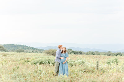 A dc newborn photographer landscape photo of a pregnant couple together in a field