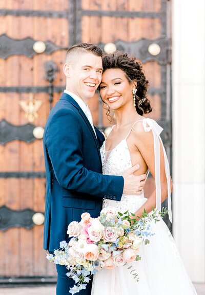 Bride and groom standing in front of door holding bouquet