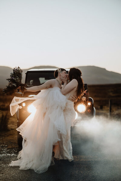 lgbtq+ couple is kissing in front of an adventure car in Scotland