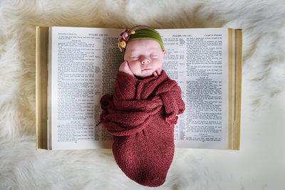 Beautiful Mississippi Newborn Photography:  Baby girl sleeps on family bible with floral head wrap