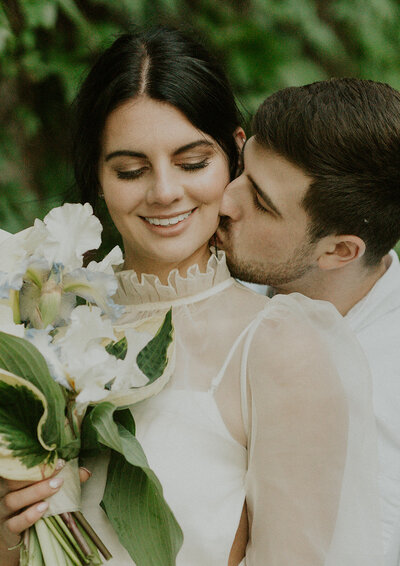 the-groom-is-kissing-bride-to-her-neck-and-she-is-smiling