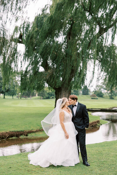 Bride and groom kiss on outdoor golf course in Harrisburg.