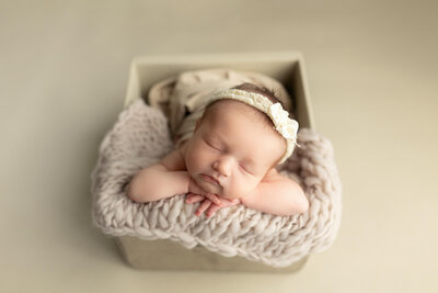 Newborn girl posed on peach fabric during her newborn photography session.