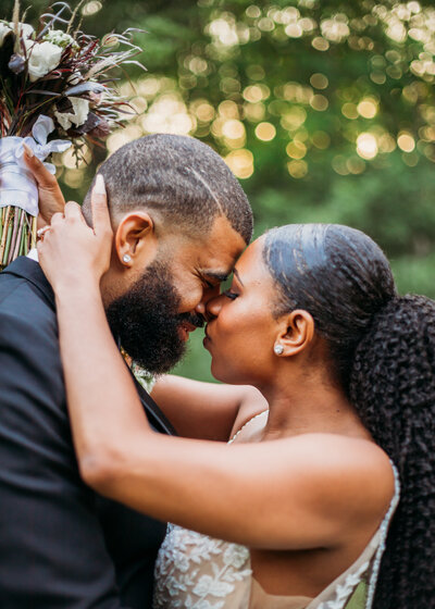 Couple embraced with foreheads touching on wedding day.