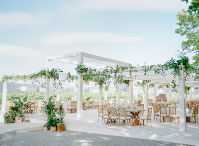 An outdoor wedding reception under white arches