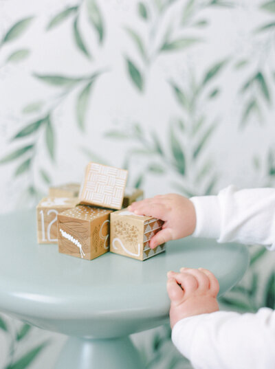 small child reaching for toy wooden blocks