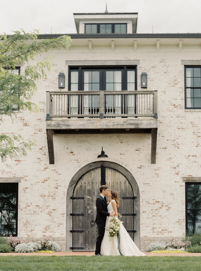 Bride and Groom kiss in front of Trinity View Farm in Nashville photographed by Nashville luxury film wedding photographer Magnolia Tree Photo Company