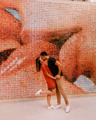couple kissing in front of mosaic wall