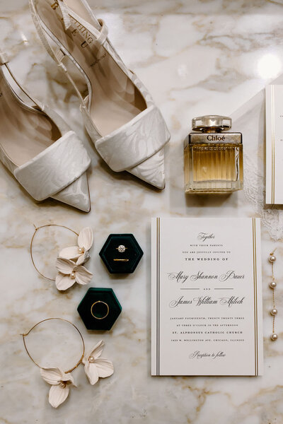 Invitation suite flatlay with bridal accessories such as shoes, colorful flowers and jewelry