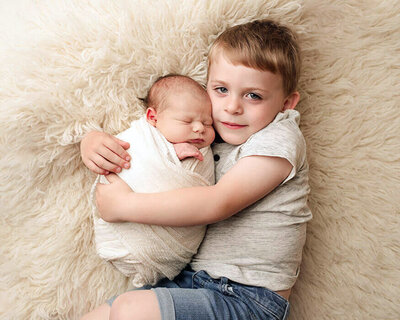 older sibling holding newborn baby