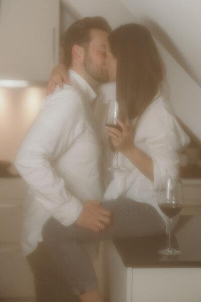 Eine Frau sitzt auf der Küchenarbeitsfläche, während der Mann vor ihr steht und sie küsst.
