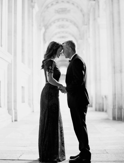Couple stand forehead to forehead under arched walkway in Paris