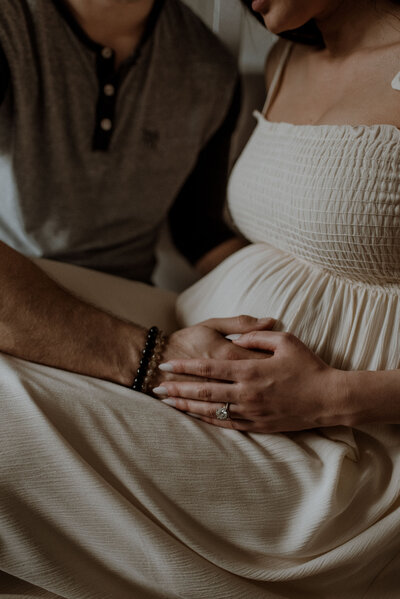 couple holding hands over a pregnant belly
