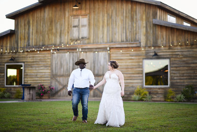 Bride and groom walk in front of barn at The Camellia Barn in MIssissippi