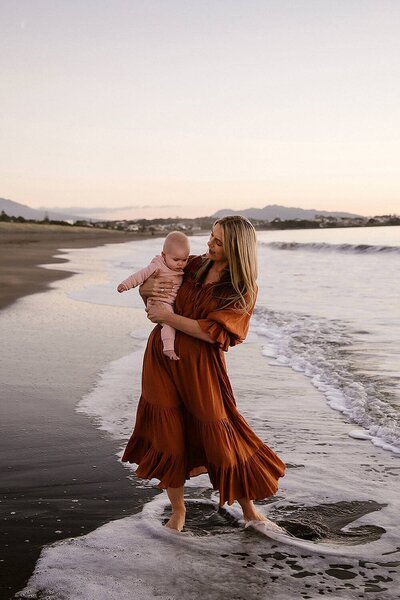 A mother swings her baby on her hip during a family photoshoot with taranaki photographer aimee kelly