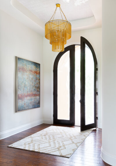 white entry way. white foyer with black steel front door. gold chandelier