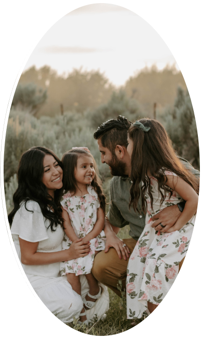 Family photo of a mom, dad, and 2 young girls in an outdoor setting with sagebrush