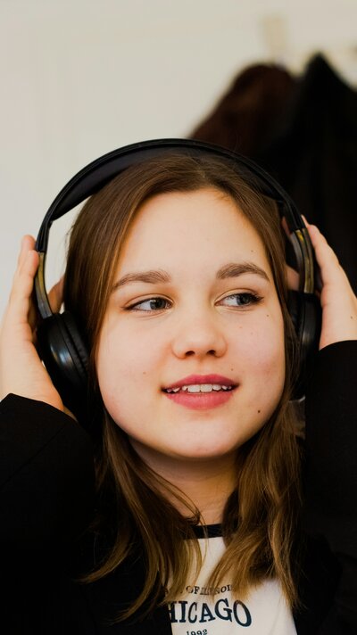 Young girl smiling while listening to music therapy, showing safe and supportive nervous system regulation for children
