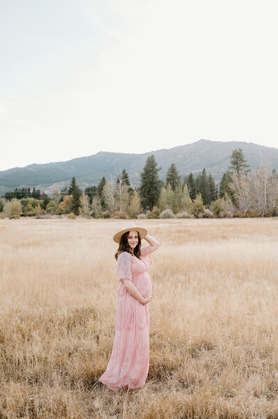 pregnant woman in field touching belly