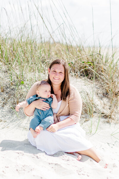 Mommy and Me Beach Mini Session sitting by dune with Ron Schroll Photography in Ocean Isle Beach, NC
