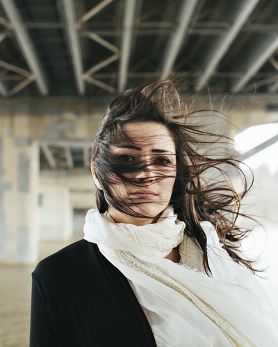 a woman wearing a scarf while her hair blows over her face