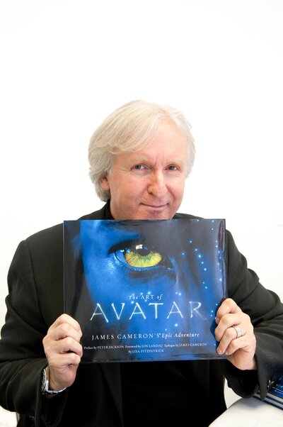 Creator of Avatar poses for a photo holding his book "The Art of Avatar"