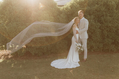Bride and groom with veil blowing in wind.