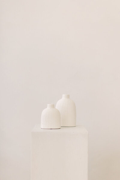 two white vases on pedistal