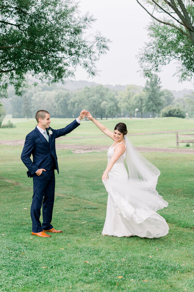 Groom spinning bride with a sweeping train and veil at a misty golf course in Green Bay, WI