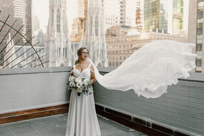 bride standing on new york city rooftop with veil blowing in breeze
