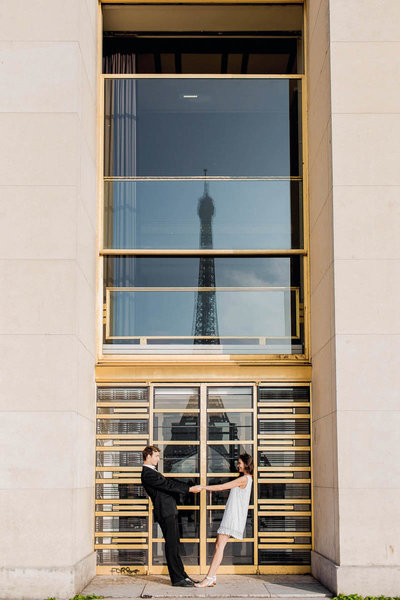 Bride and groom snuggle with the Eiffel Tower reflected in the glass, Paris, France, Destination Wedding Photographer