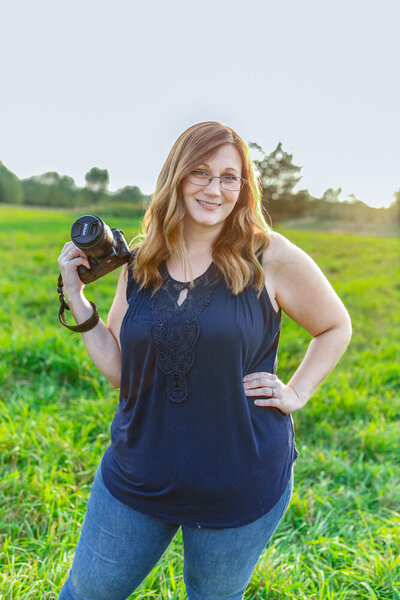 woman standing in a field holding a camera