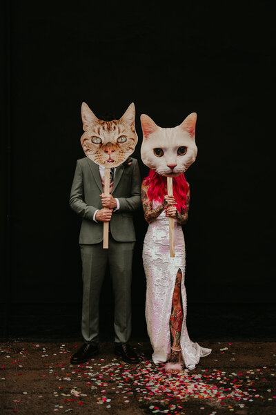 A tattooed couple hold up cut outs of their cats at their Manchester wedding.