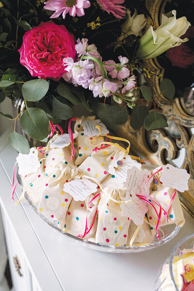 Polka dot favor bags in pink and yellow with gold foil thank you tags elegantly displayed in a crystal bowl for a girl baby shower.