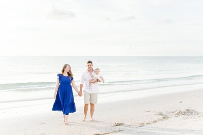 parents walking on the beach with their baby