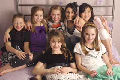 Mobile spa party for pre-teens. Girls sitting together showing off their manicures and makeup.