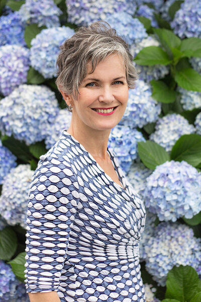 Headshot of Lucy in front of blue hydrangeas
