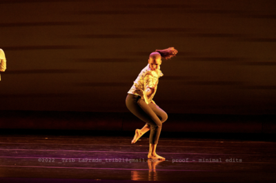 Amber Daniels in a modern dance position with one leg on the ground, the other is bent and pointed behind her.