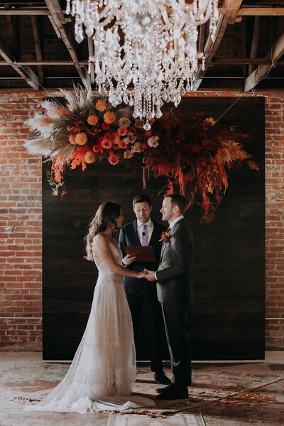 wedding ceremony at the St Vrain with large red and orange floral overhang