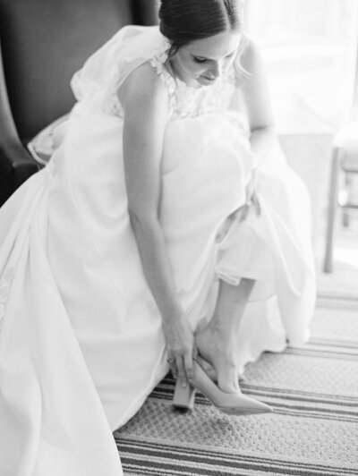 black and white image of bride putting her shoes on