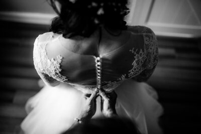 Luxury Wedding Portraits by Moving Mountains Photography in NC - Black and white photo of a bride having her wedding dress buttoned up.