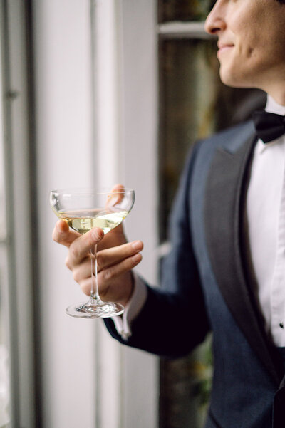 Groom holds old fashioned champagne glass