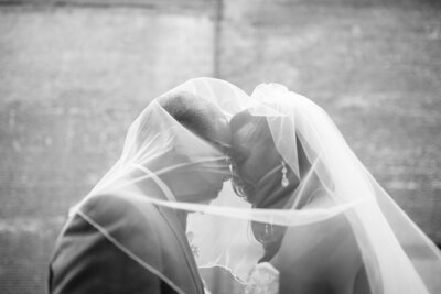 Monochromatic photo of two newlyweds under the bride's veil