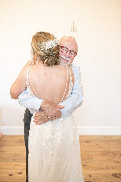 Father of the bride hugs his daughter on her wedding day