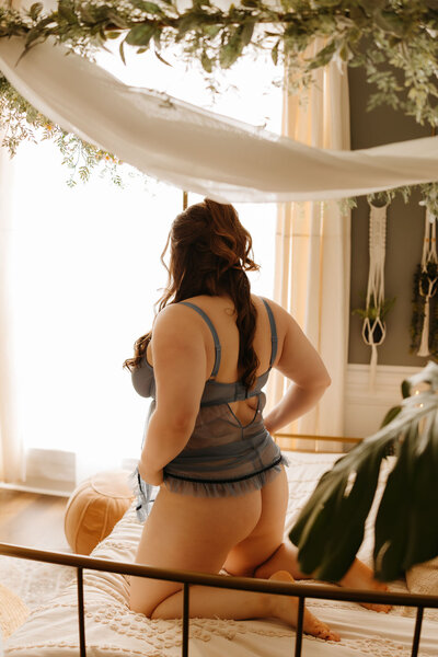 woman looking at herself in mirror, standing in bra and underwear