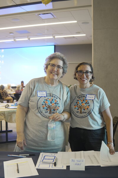 Two Friends of the Library Smiling at the sign-in table
