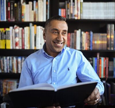 male life coach sitting with lots of books on shelf behind him