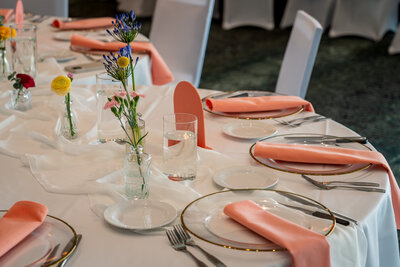 Table setup with modern floral arrangements and coral napkins – photographed by wedding photographer Niko Coric – Lumen Clarity Media