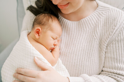 Mom cuddles sleeping newborn baby boy during lifestyle newborn session by Worth Capturing